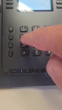 close up of a hand dialing a phone number in the office
