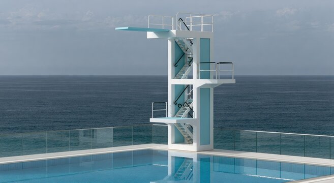 Tall diving platform overlooks a bright blue pool and ocean under a hazy sky