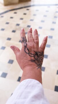 woman with simple henna mehndi design showing her hand on tiled floor background