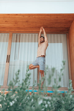 Man stretching on a terrace at home, enjoying a calm wellness routine. Concept of good health, wellbeing, flexibility, and balanced lifestyle in a modern outdoor living space