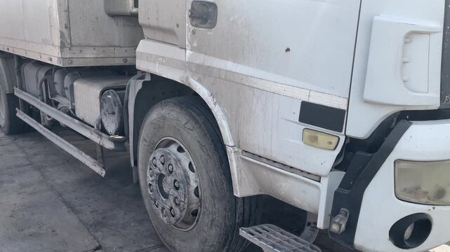 Dirty heavy duty truck side and front wheel before washing, showing dust, grime and road residue on the commercial vehicle exterior, prepared for professional cleaning and maintenance service.
