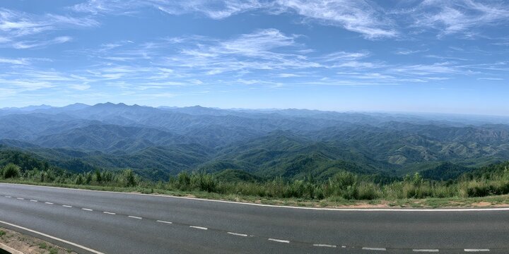 Wide panoramic vista of lush green, rolling mountains under a bright blue sky