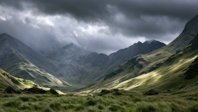 Sunlit valley between dramatic, shadowed mountains under stormy skies