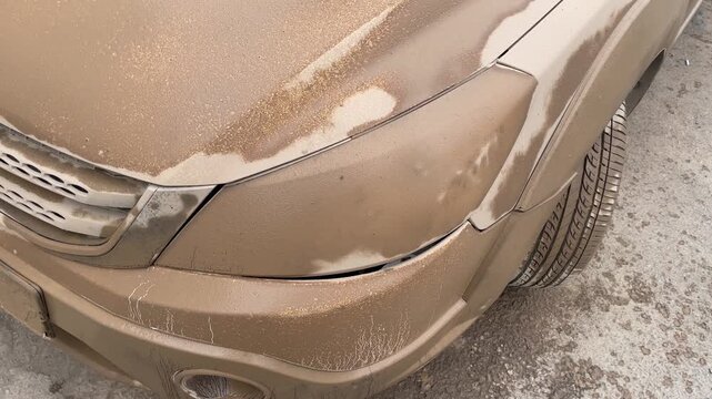 Mud covered hood and front fender before washing, revealing thick layers of dirt and road grime on the vehicle body, perfect for automotive cleaning and detailing stock projects.