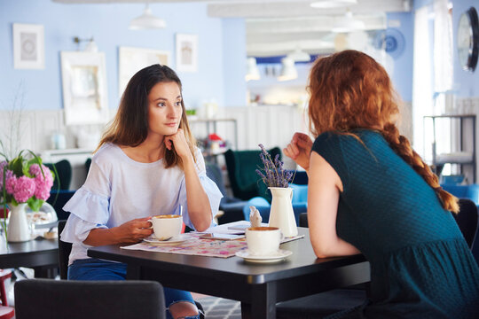 Two women talking and drinking coffee at cafe