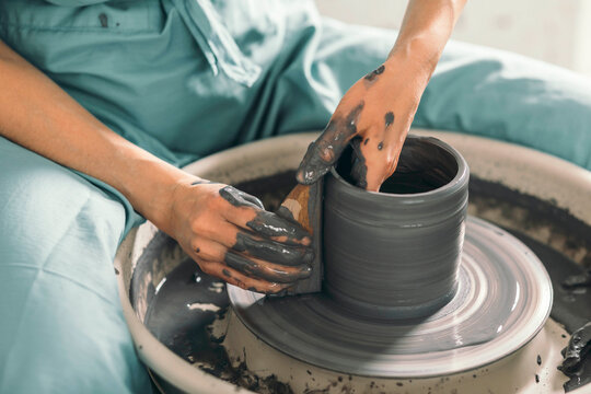 Hands of potter shaping ceramic pot at workshop