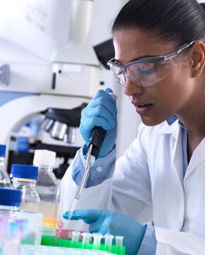 Genetic research, female scientist pipetting DNA or chemical sample into a eppendorf vial, analysis in the laboratory