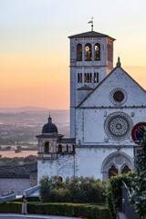 Naklejka premium Basilica of Saint Francis at Sunset with the Distant Umbrian Plain. Medieval Religious Architecture in Golden Evening Light, Assisi, Italy