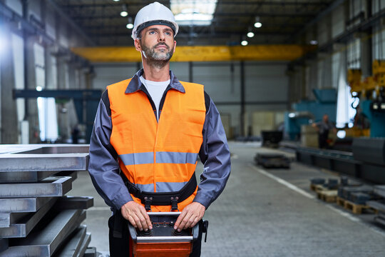 Portrait of man in factory operating machinery with remote console