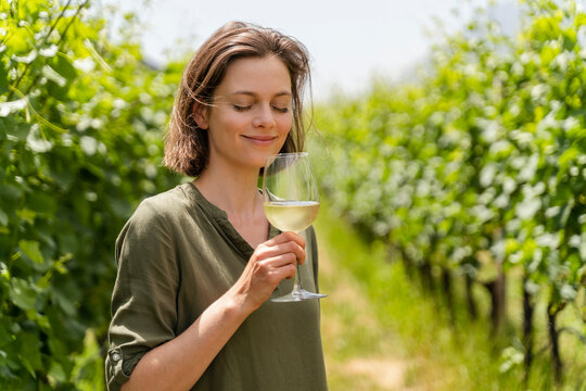 Smiling woman smelling wine while standing at vineyard