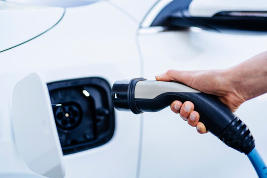 Woman plugging charger in electric car at station