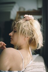 Side profile portrait of young blonde woman touching her hair, gentle daylight and natural beauty, shot on 35mm film © Anastasia