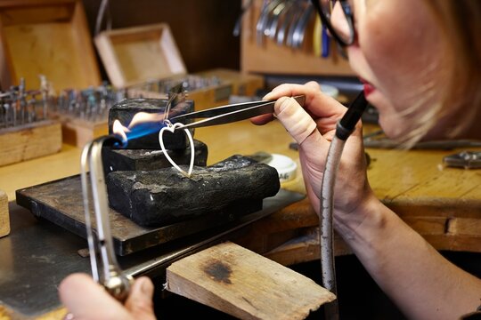 Goldsmith in workshop soldering heart