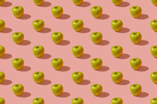 Pattern of green apples against pink background