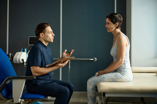 Male physiotherapist consults woman patient in clinic