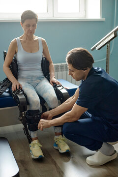Physiotherapist helps woman with exoskeleton in clinic