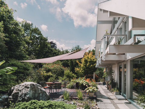 Modern villa with lush garden and patio under a sunshade