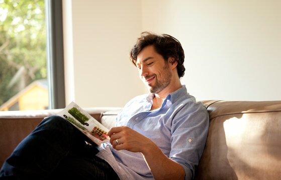Man sitting on couch reading catalogue