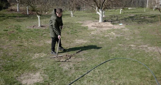 Kid Rakes Grass on Lawn. Caucasian Boy Help Working Around Backyard. 4K 10-bit