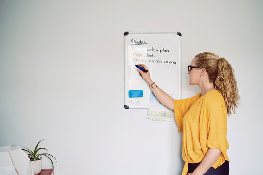 A woman writes ideas on a whiteboard in her London home office