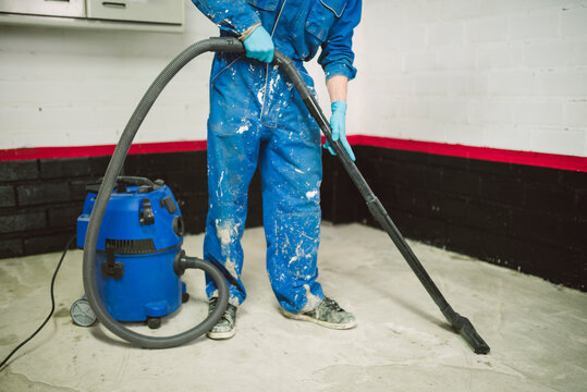 Bricklayer cleaning the floor with an industrial vacuum cleaner