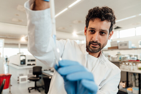 Scientist examining liquid in pipette at laboratory