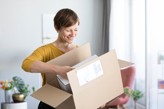 Smiling woman unpacking parcel at home