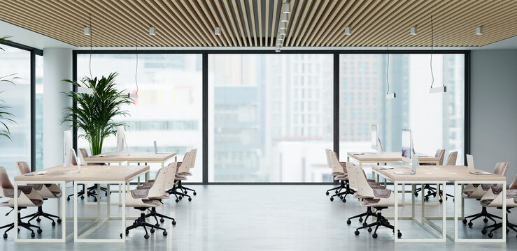 Modern open office workspace features empty desks and large windows