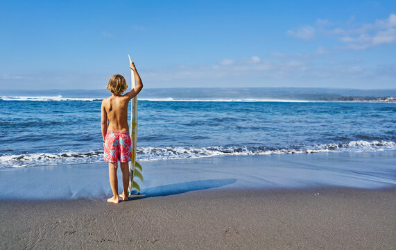 Chile, Pichilemu, boy standing at the sea with surfboard