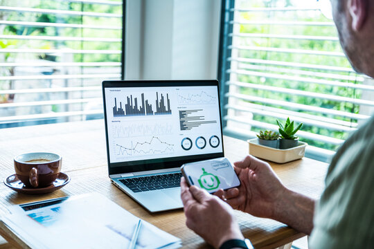 Man uses AI chatbot on mobile while analyzing data at the office