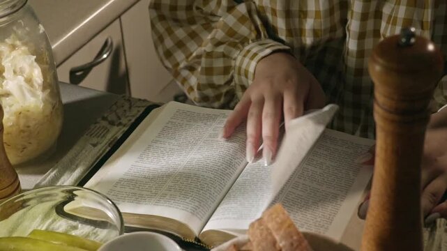 young conservative asian Woman Reading the Bible at table with bread food and drink indoors	