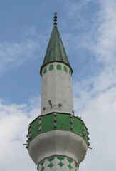 Naklejka premium Short Ottoman era Minaret painted Green and White with Blue Sky Background in Sarajevo, Bosnia and Herzegovina