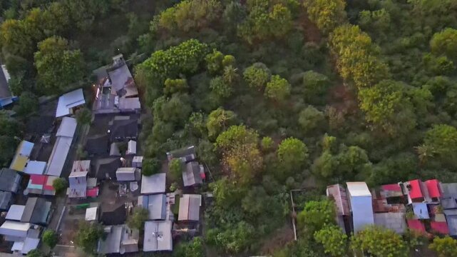 A high-angle panoramic aerial drone photograph capturing the main building complex of Sylvia Resort (Silvia Resort) nestled at the foot of green tropical hills in Labuan Bajo. The central focal point 