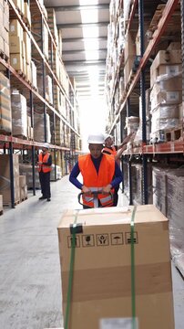 Logistics employee operating a hand pallet truck in a large distribution center. Warehouse workers managing inventory and shipment in slow motion