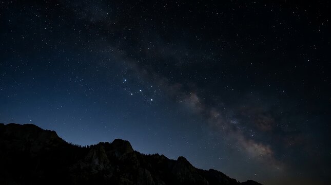 Starry night sky with milky way over dark mountain peaks