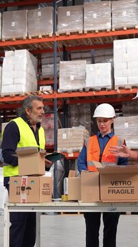 Team of workers at a logistics distribution center packing fragile goods. A supervisor oversees the process while employees prepare boxes for shipment