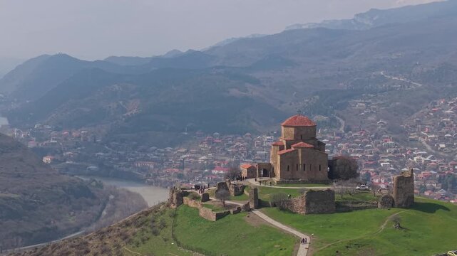 Sunny spring day capturing Jvari Monastery above a lush green landscape, with the river flowing at the bottom of the hill near Mtskheta.