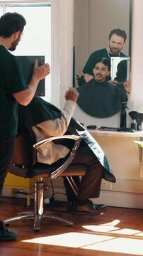 Barber, man and discussion for hairstyle with mirror, smile and customer satisfaction for grooming. Hairdresser, person and talk in salon with reflection, consultation and happy for hair makeover.