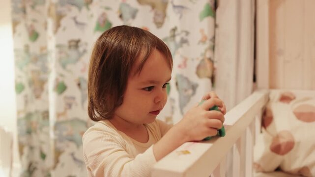Curious 3 year old girl exploring a green dragon toy during imaginative play at home