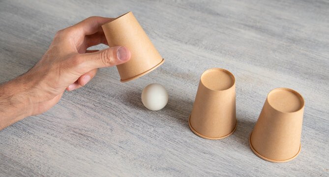 Magician shows game of thimbles with a cups.