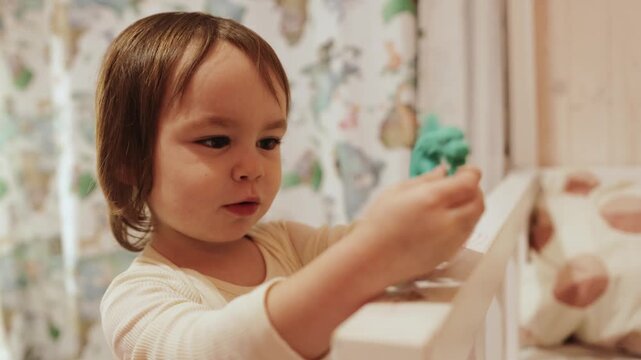 Little girl happily playing with a green dragon toy inside a warm wooden family home
