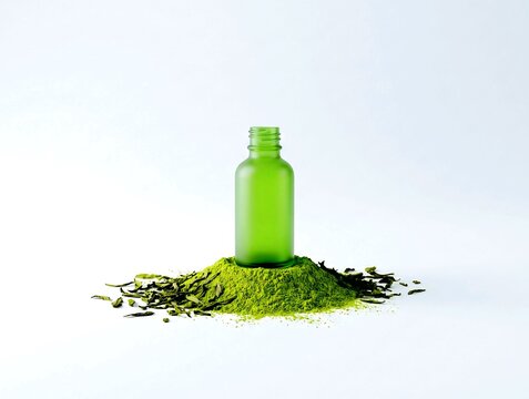 Blank frosted green serum bottle on matcha powder with dry green tea leaves