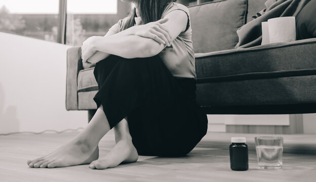 Young Asian woman sitting in bed and holding her head in pain with headache, feeling depressed 

and suffering