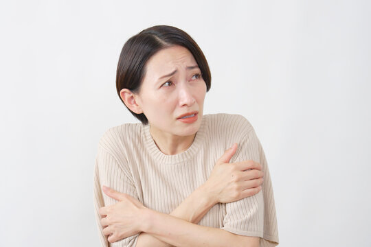 白背景で寒さに震える40代女性