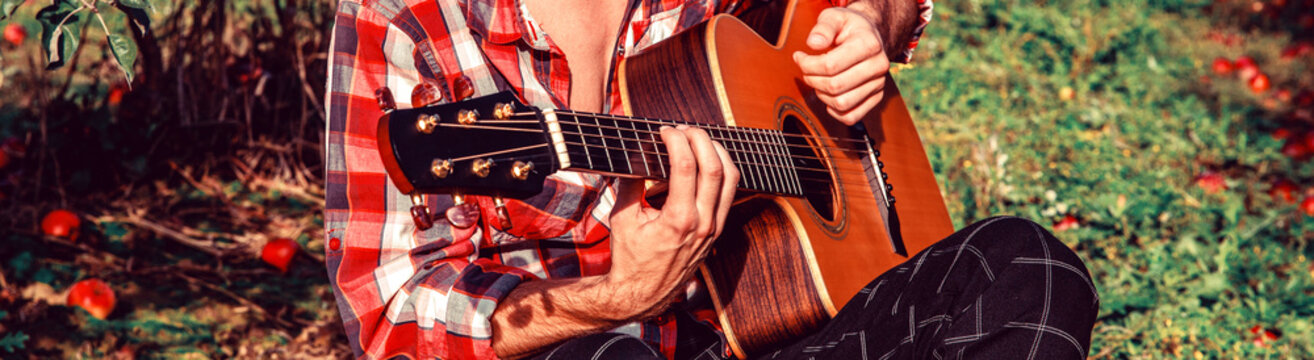 Man's hands playing acoustic guitar. The man sings and plays the acoustic guitars