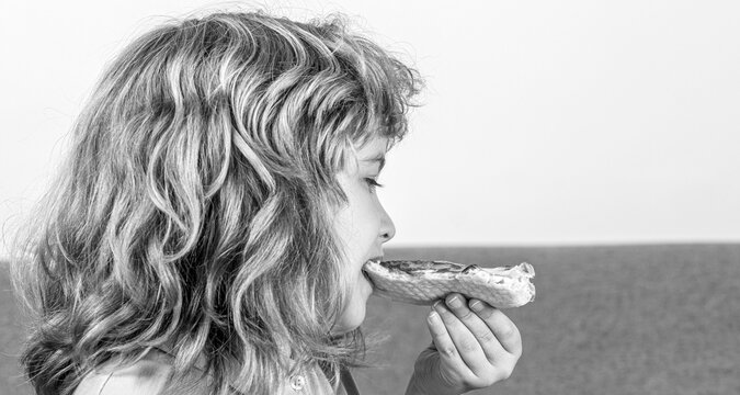 Kids love pizza. Boy enjoys eating pizza. Little boy eats a slice of pepperoni pizza. Black and white