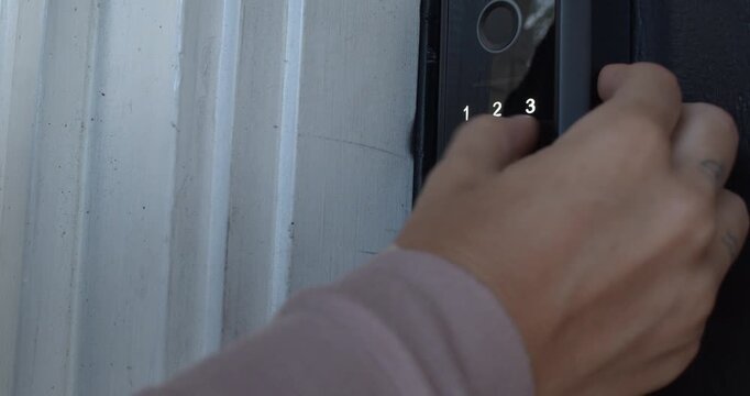 Close up technology footage showing a hand that enters a numerical code into a keypad smart lock before unlocking and opening the door for secure keyless access.
