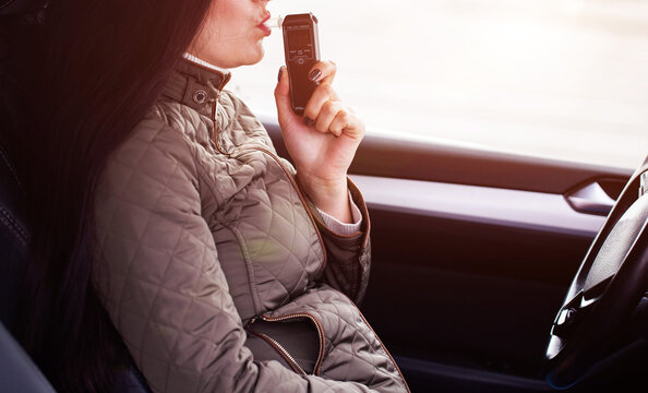 Female Driver Testing Breath For Alcohol Content Inside Automobile. Personal Sobriety Measurement. Copy space for text