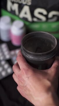 Top view of man adding second scoop of weight gainer powder into fitness shaker