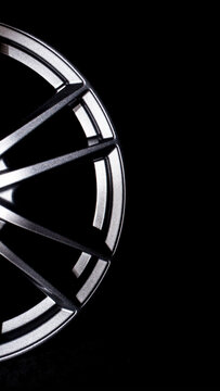 Close up view of metallic silver car wheel rim with spokes against dark background highlighting modern automotive design and sparkling texture vertical photo